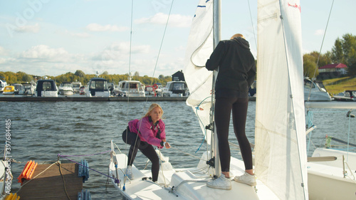 Teamwork of young athletes. Girls together raise the sail on their own fast sports yacht.