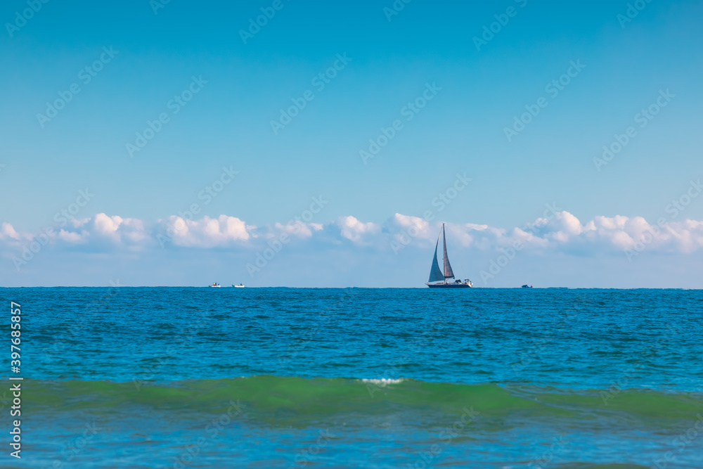 Obraz premium Sailboat over blue waves and sunny sky. Sea and sailing wind boat