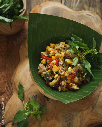 Cakalang Jagung Manis is stir fried shredded skipjack tuna and sweet corn with spices and herbs, originally from Manado. top angle, wooden table.  photo