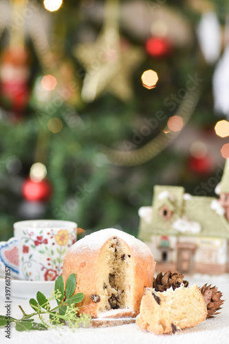 Mini Panettone (Italian Christmas cake) with candied fruit with blurred Christmas lights flashing in the background. Vertical