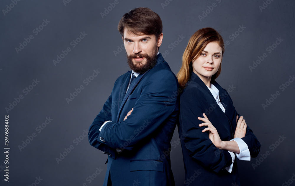 Business successful people in suits stand with their backs to each other on a gray background confident look Business successful people in suits stand with their backs to each other on a gray background confident look