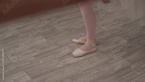 Before the rehearsal, the ballerina puts on pointe shoes, sitting on the floor, stands up and stretches her feet photo