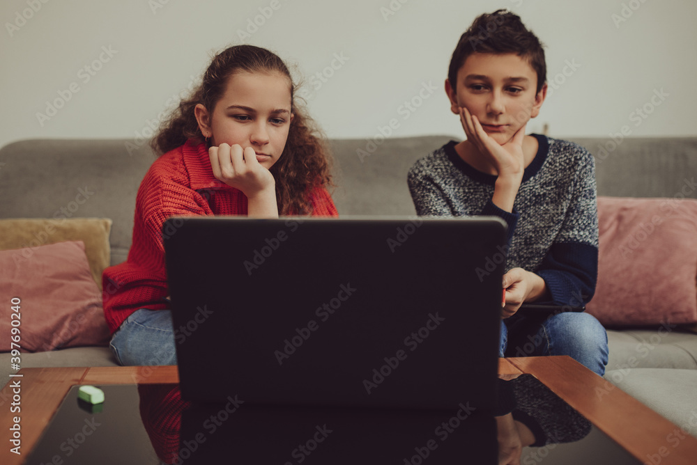 Boy and girl having online school class, e-education.Boy and girl attending online classes from home.Childs using laptop for connecting with teacher and schoolmates.School education and social distan