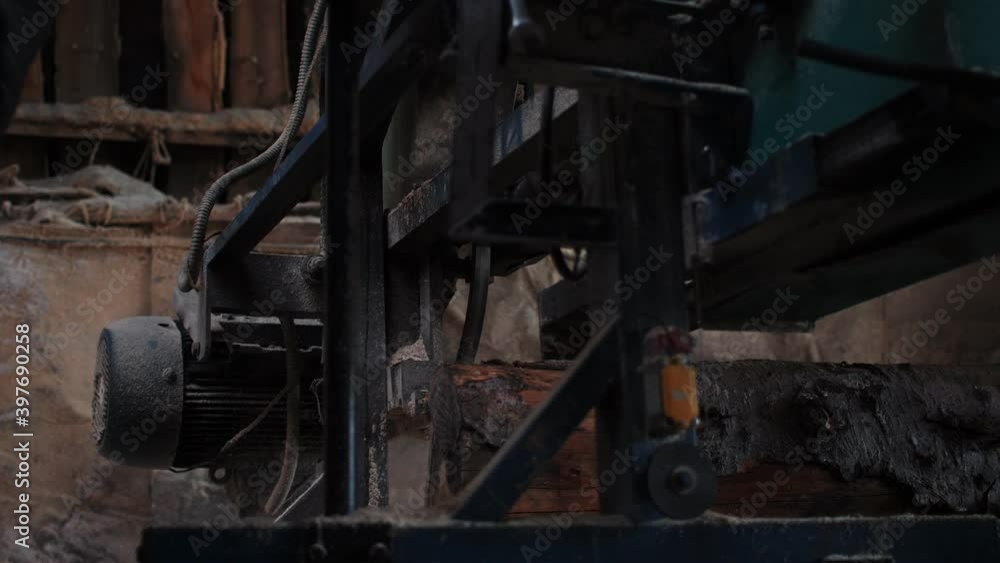 Sawing machine cuts large log lying on long workbench Sawing machine cuts large log lying on long workbench