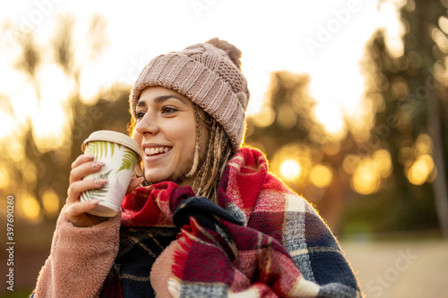 Young woman with coffee cup smiling outdoors during winter  © pikselstock