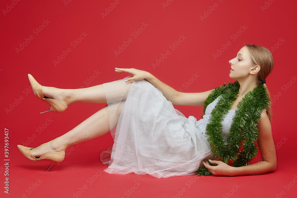 Naklejka premium attractive girl lying with a christmas ornament on a red background