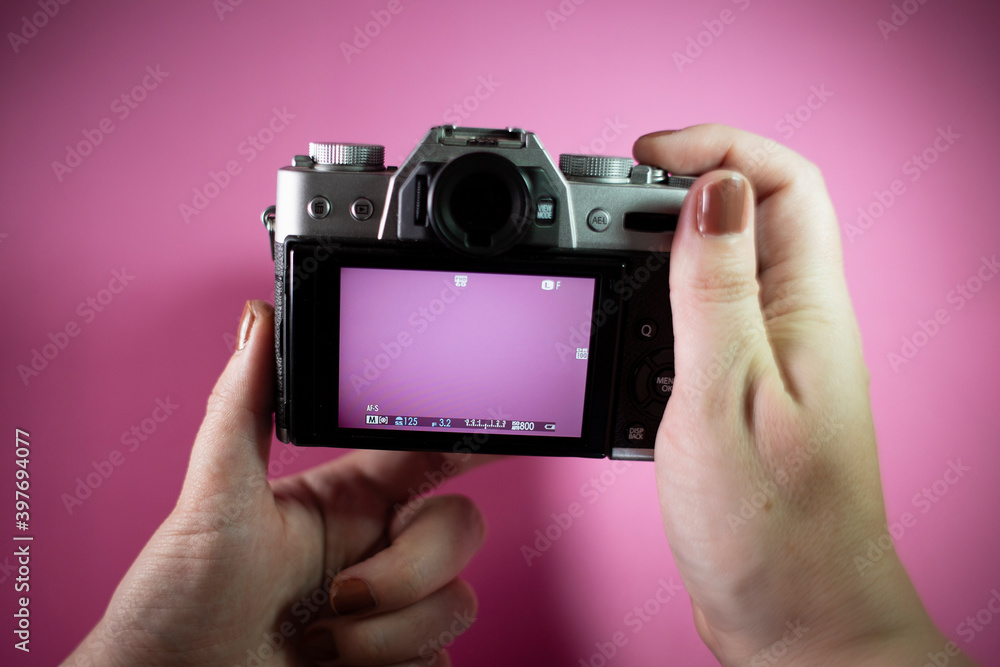 Woman's hands with a photo camera. Pink background Woman's hands with a photo camera. Pink background