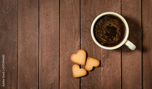 Hear shaped cookies and a cup of coffee on wooden table. Copy space.