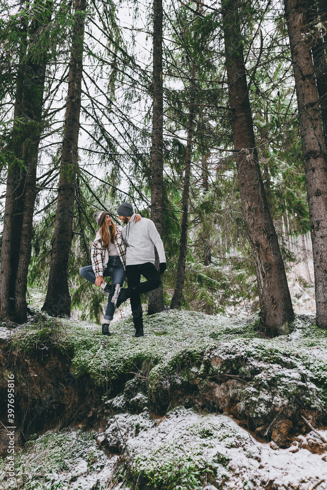Obraz premium Couple among high fir trees with first snow