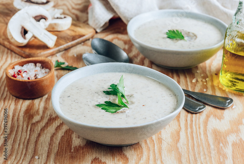Mushroom cream soup in gray bowls with parsley on wooden background