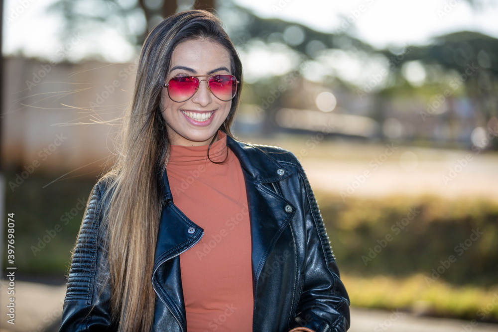 beautiful latin american woman wearing sunglasses smiling looking at the camera, on a beautiful sunny summer day beautiful latin american woman wearing sunglasses smiling looking at the camera, on a beautiful sunny summer day