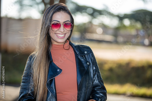 beautiful latin american woman wearing sunglasses smiling looking at the camera  on a beautiful sunny summer day