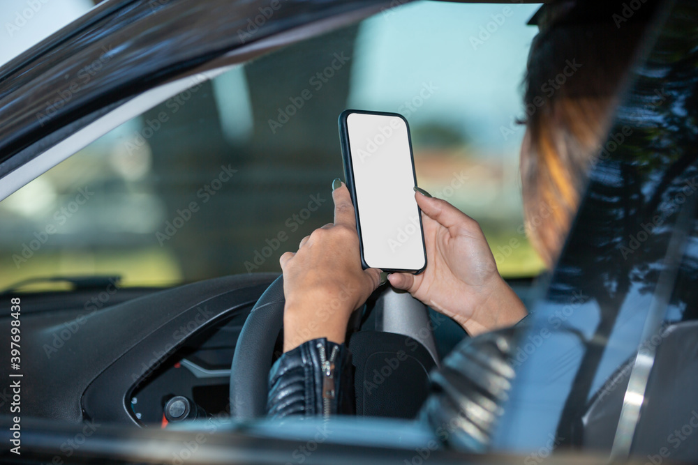 beautiful latin american woman leaning on a car looking at cell phone