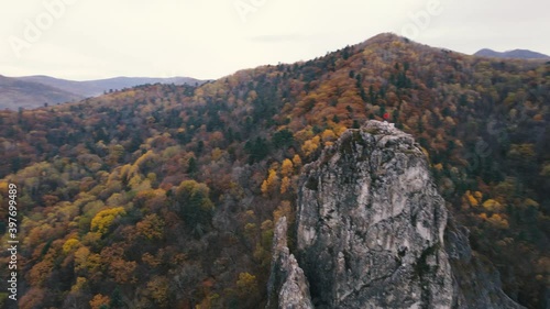 View from above. 4K. Dersu Uzala rock in the village of Kavalerovo, seaside region. The camera flies over the top of a high cliff against the backdrop of an autumn forest. photo