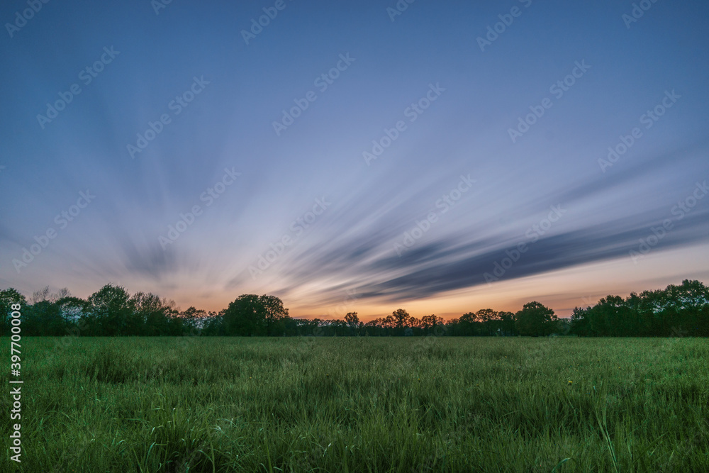 Landscape in Munsterland Germany at evening sky with moving clouds in long exposure