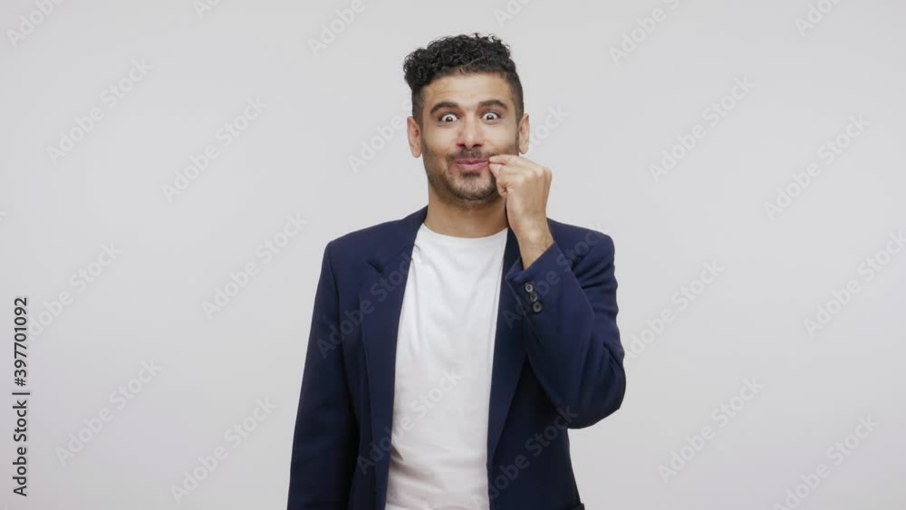 Funny cheerful man with beard pretending to close his mouth and throwing up key, swearing to be silent and keep secrets. Indoor studio shot isolated on gray background Funny cheerful man with beard pretending to close his mouth and throwing up key, swearing to be silent and keep secrets. Indoor studio shot isolated on gray background