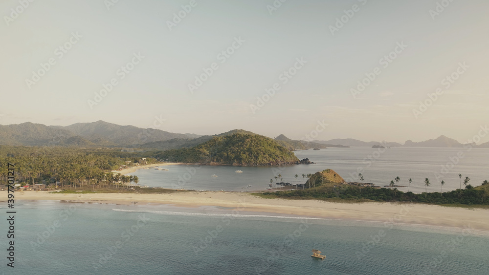 Green mountains island at ocean bay aerial. Tropic nobody nature seascape. Serene sea water at sand coast. Summer paradise at Philippines, El Nido Islet. Cinematic rise up drone shot