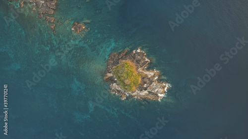 Top down of rock island with green peak aerial. Ocean waves crash on cliffs. Nobody tropic nature seascape at summer day. Epic sea bay with greenery isle. Cinematic Philippines landscape