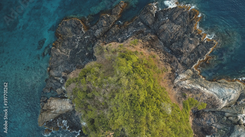 Top down closeup at green island at sea bay aerial. Nobody nature landscape of El Nido Islet, Philippines, Asia, Visayas Archipelago. Tropical exotic trees at rock isle top. Greenery plants on cliff