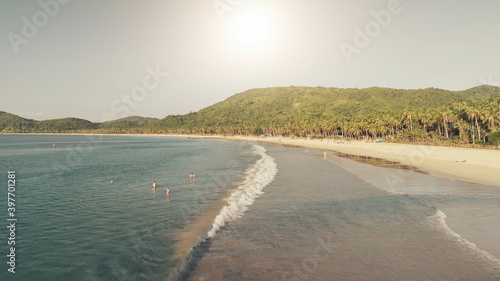 Sun over sand beach at sea coast aerial. Summer tropic paradise vacation at ocean bay. Nature landscape and seascape of El Nido Island, Philippines, Asia. Cinematic people relax at sunny day