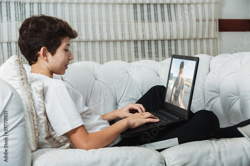 young latin american man watching a video lesson on the computer sitting on the sofa at home