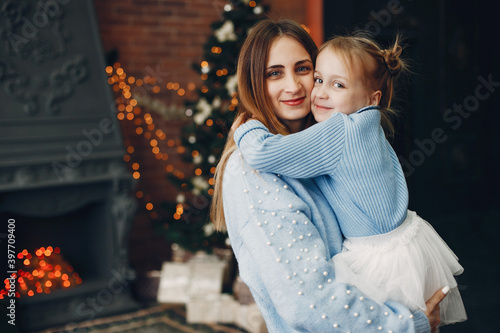 Beautiful mother in a blue sweater. Family with cristmas gifts. Little girl near christmas tree © prostooleh