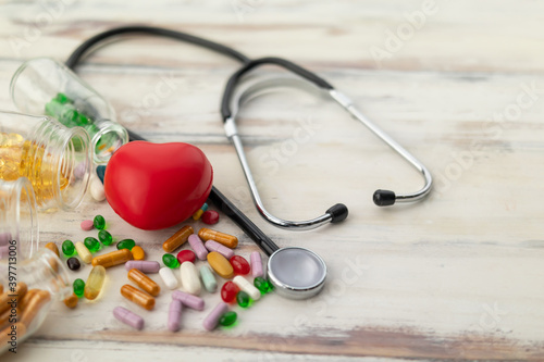 Top view of red heart and medicine on wooden floor