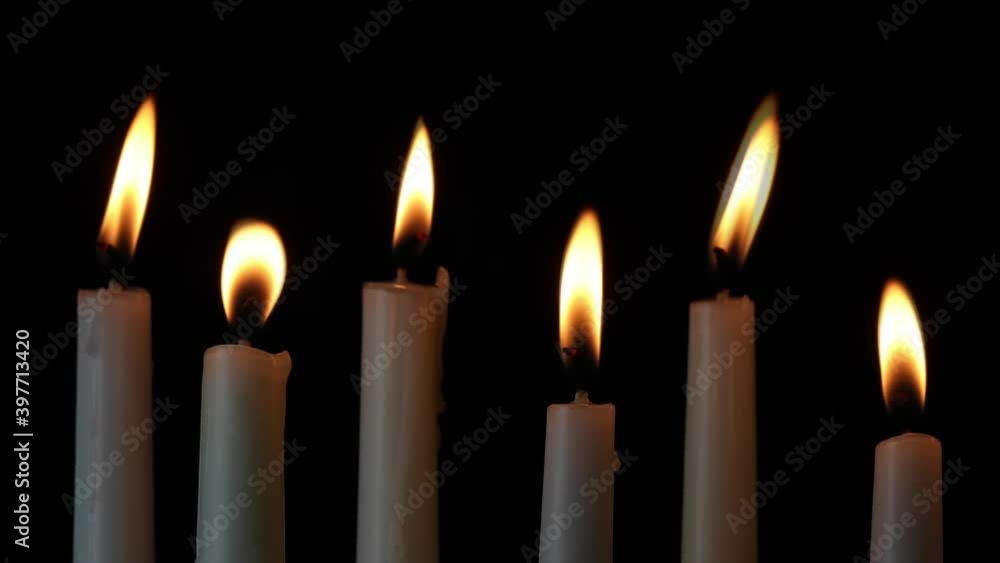 Six tall, white taper dinner candles, with flickering flames burning, light the darkness against a black background in this looping video footage. Six tall, white taper dinner candles, with flickering flames burning, light the darkness against a black background in this looping video footage.
