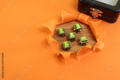 Traditional Malay costume buttons in green gems isolated on the wooden table with an orange color and torn paper effect  photo