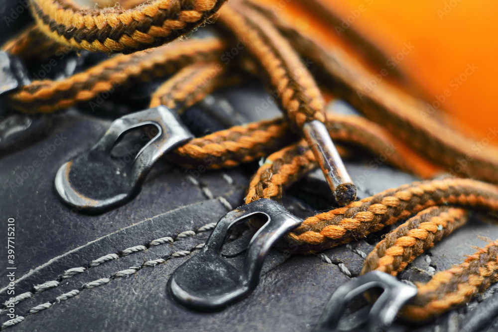 Metal buckles of work leather shoes with tied laces close up on yellow background. Shallow DOF