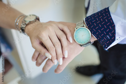 Hands of stylish young couple with wristwatches - Female hand with white nails and hand of executive man wearing social clothes