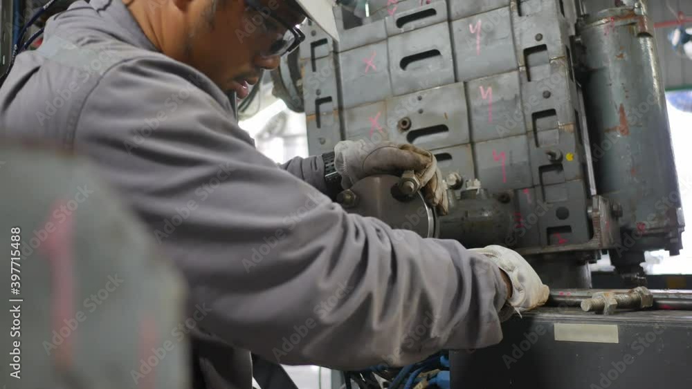 Mechanics are servicing the machines in the factory to prepare for the next production run. Mechanics are servicing the machines in the factory to prepare for the next production run.