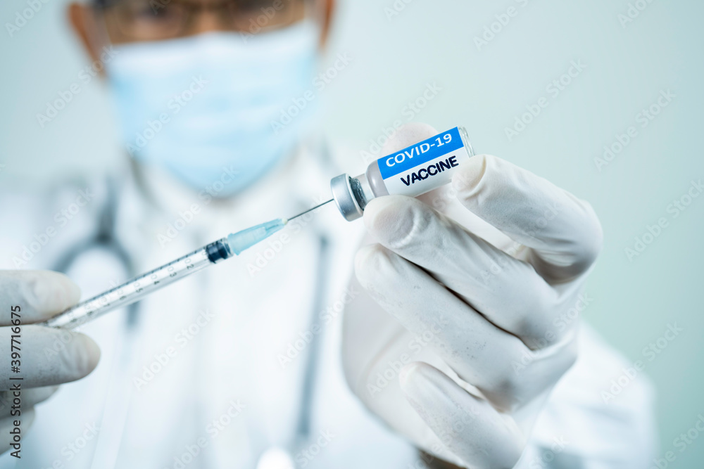 Selective focus, The COVID-19 vaccine is ready for use. Doctor with a stethoscope on shoulder holding syringe and COVID-19 vaccine.COVID-19 vaccine concept. Selective focus, The COVID-19 vaccine is ready for use. Doctor with a stethoscope on shoulder holding syringe and COVID-19 vaccine.COVID-19 vaccine concept.