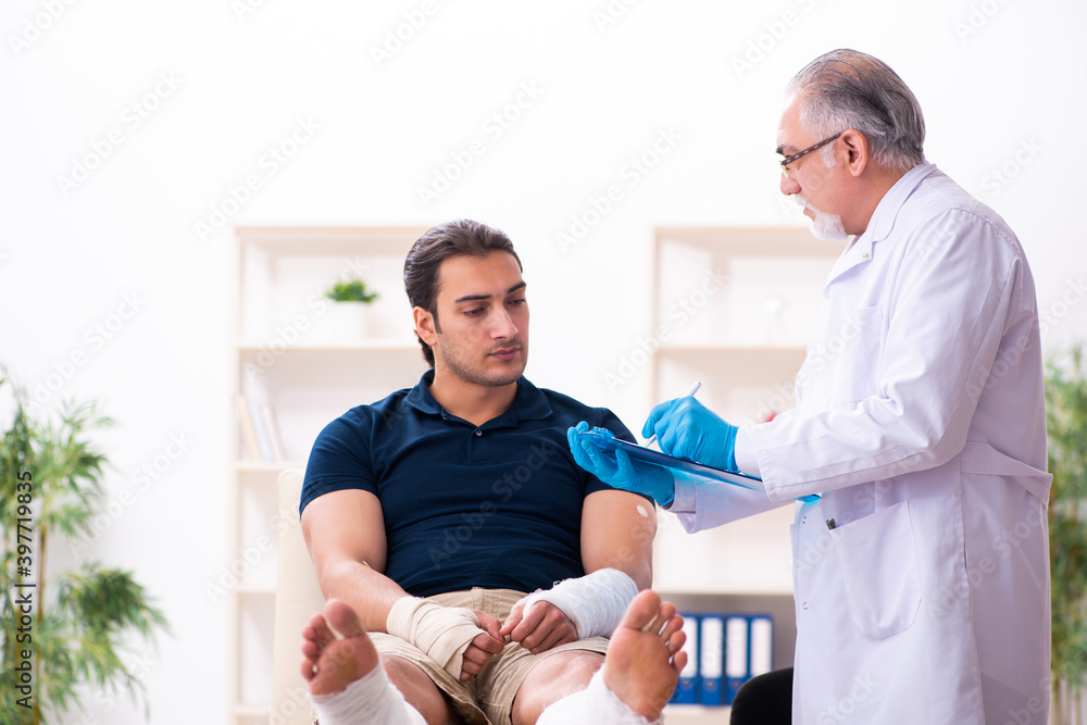 Fototapeta premium Young injured man visiting old doctor traumatologist