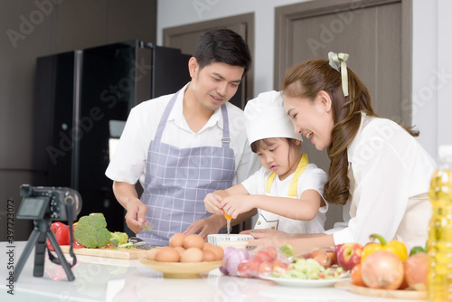Asian family enjoys cooking together and recording video about tutorial homemade cooking at home kitchen. Person who works freelance on social media broadcasting  Activities together family.