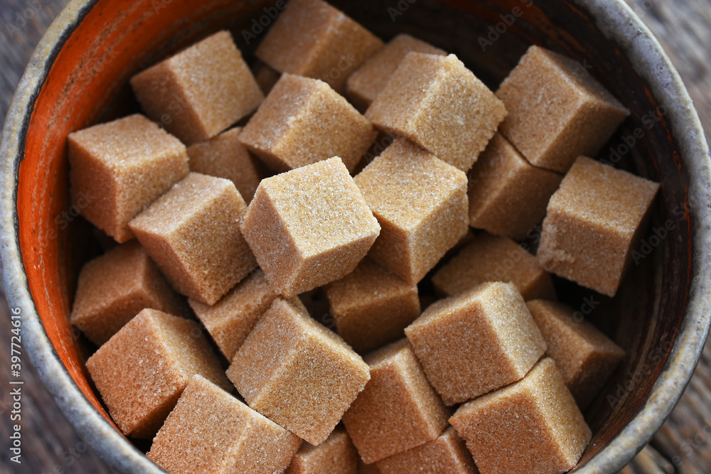 A close up image of several brown sugar cubes in an hand made pottery bowl. 