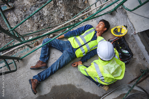 Check Response and pulse, Life-saving, and rescue methods. Builder accident falls scaffolding on floor, Safety team helps employee accident. First aid support accident in Construction work. photo