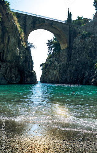 Fiordo di Furore, Amalfi coast, picturesque seascape view from beach on arched bridge between rocks and turquoise sea.