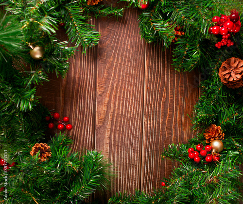 Christmas frame decoration with berries, cones and Christmas tree branch on the wooden background. Copy space.