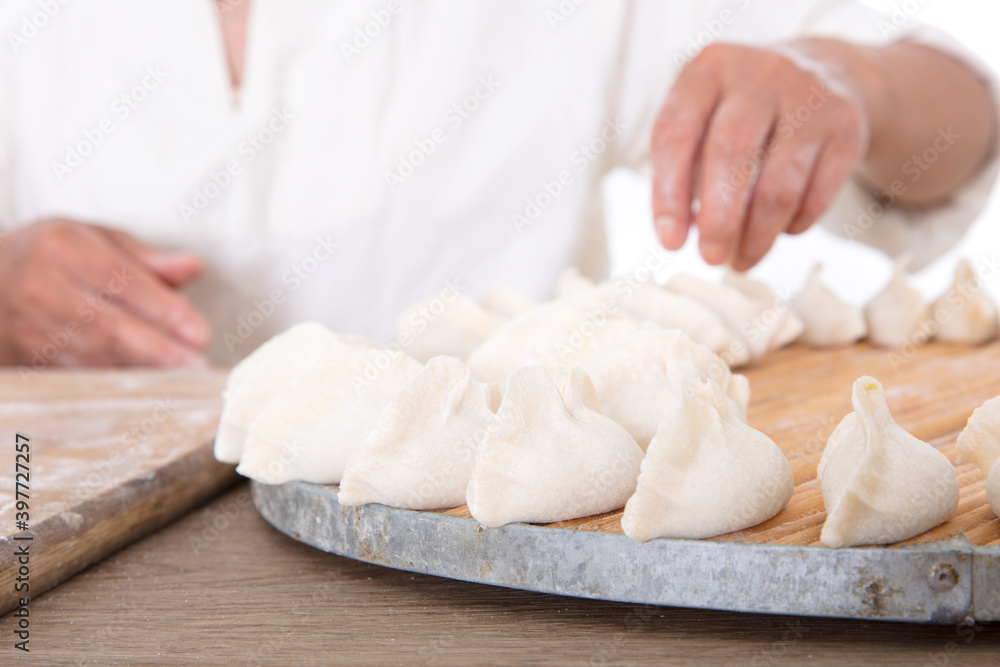 Chinese women are putting the wrapped dumplings on the round tray