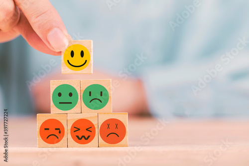 Hand chooses with happy smile face emoticon icons on Wooden Cube , good feedback rating for customer review survey photo