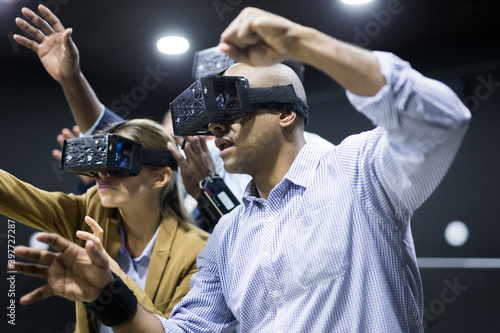 Portrait of young adult man with virtual reality glasses standing in dark room