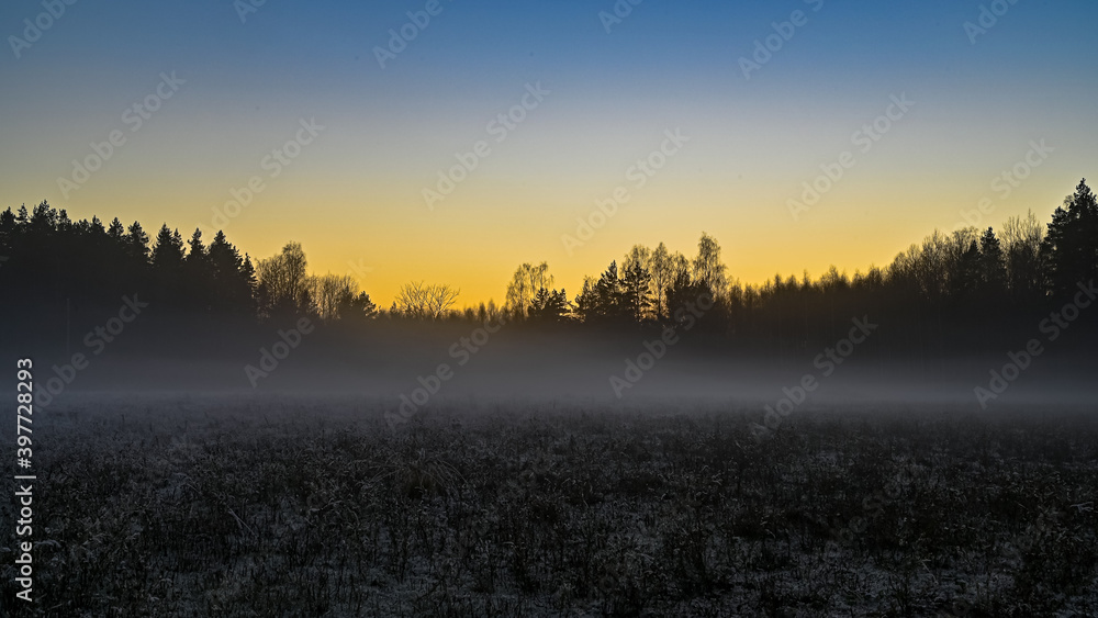 Obraz premium sunset over a misty field in Sweden