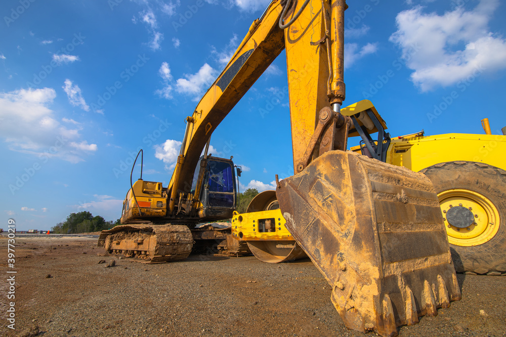 Backhoe and road roller on the ground at site construction. Backhoe and road roller on the ground at site construction.