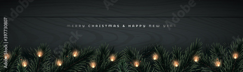 Realistic pine tree branches, pine cone and glowing garlands on black wooden background. Long vector banner for Christmas and New Year celebration with copy space.