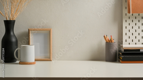 Worktable with stationery, frame, cup and decorations in home office