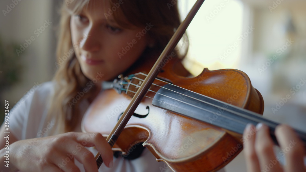 Girl playing violin at home. Violinist playing chords on musical instrument Girl playing violin at home. Violinist playing chords on musical instrument