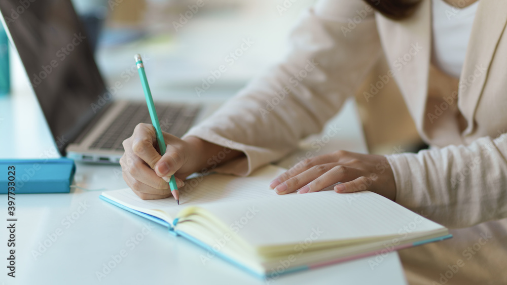 Female hand writing on blank notebook while working in office room Female hand writing on blank notebook while working in office room