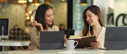 Two businesswomen consulting on their project with tablet in meeting room