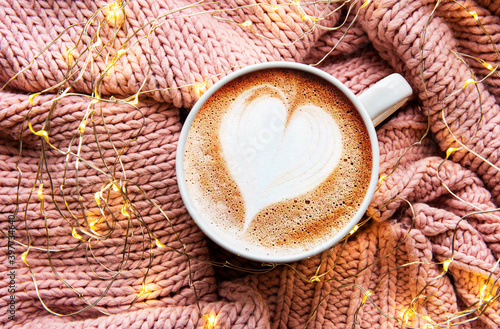 Coffee with a heart pattern on a warm knitted sweater